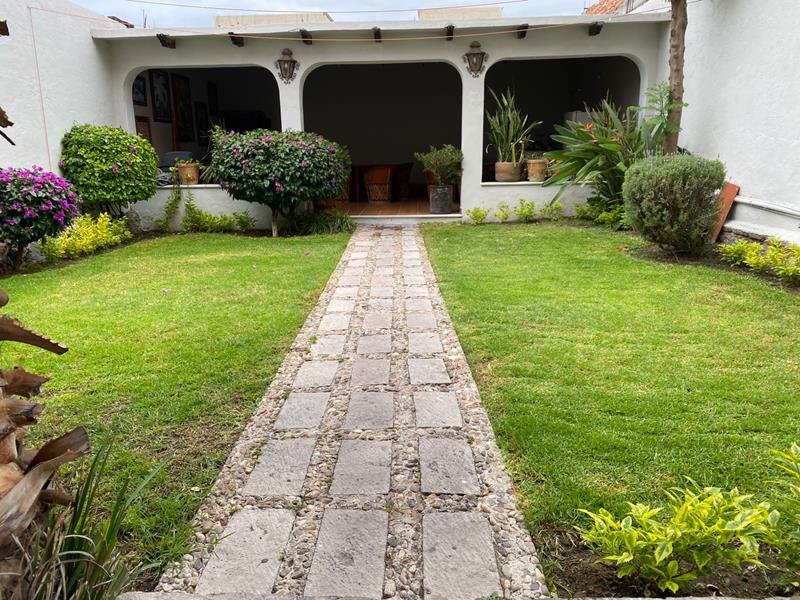Jardín con sendero de piedra y portal de arcos