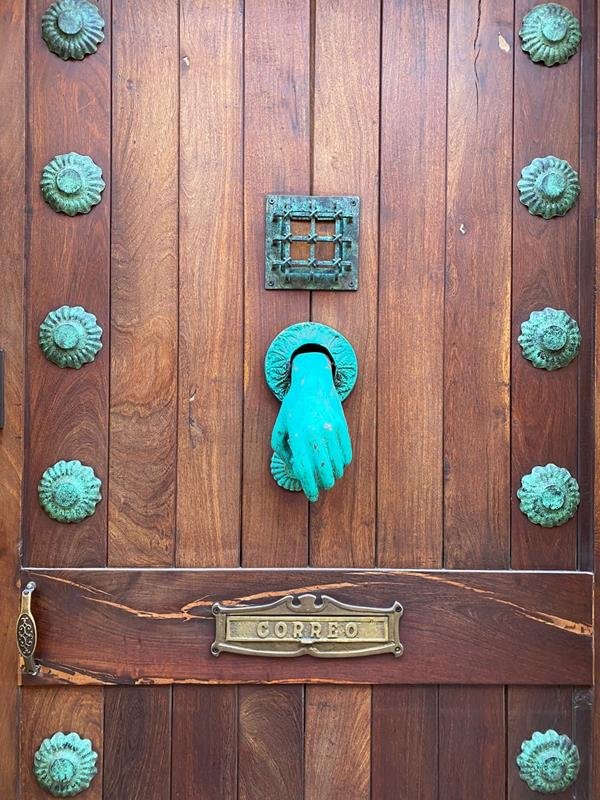 Puerta de madera con aldaba en forma de mano