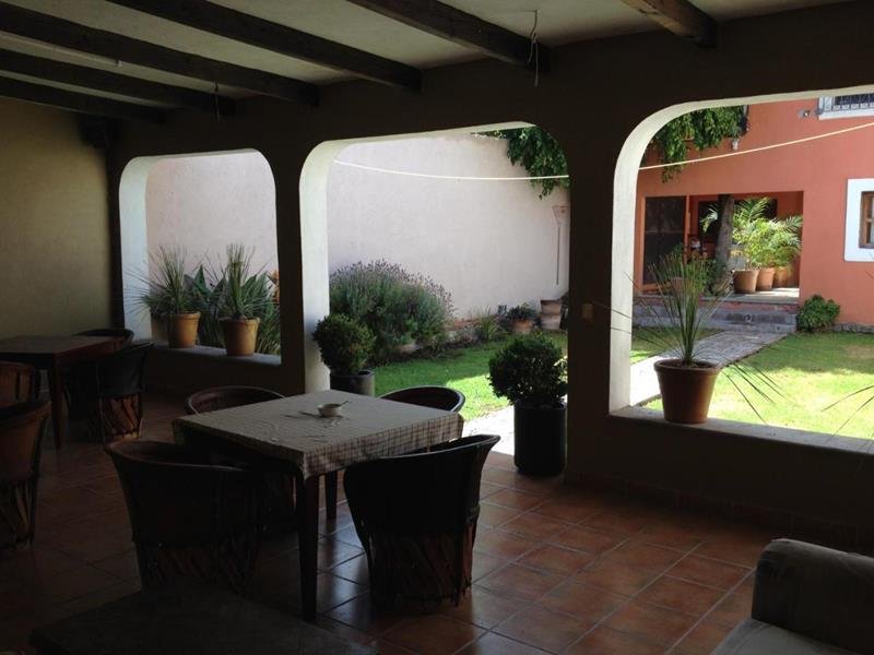Terraza techada con arcos y mesas frente al jardín